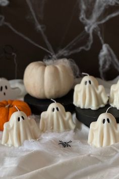 halloween candles with ghost faces and pumpkins in the background on a white tablecloth