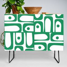 a green and white cabinet sitting next to a potted plant on top of a table