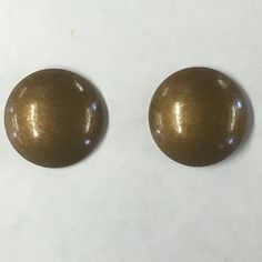 two shiny gold colored buttons on a white surface