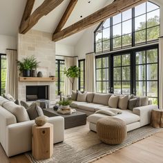 a living room filled with lots of furniture next to a fire place and large windows