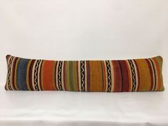 a colorful striped pillow sitting on top of a white bed