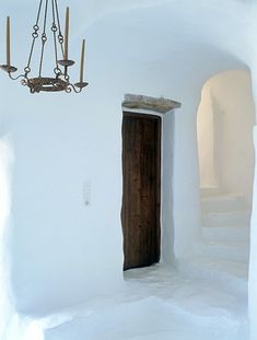 a chandelier hanging from the side of a white wall next to a doorway