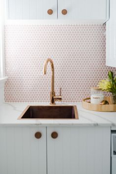 a kitchen sink with a wooden cutting board on the counter top and white cabinets behind it