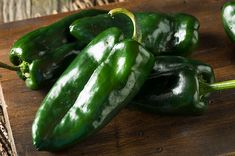 several green peppers on a wooden cutting board