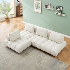 a large white sectional sofa sitting on top of a hard wood floored living room