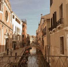 a narrow canal runs between two buildings on both sides, with a bridge in the foreground