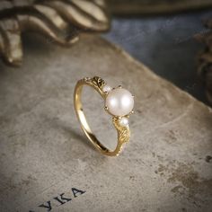 a gold ring with two pearls on it