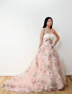 a woman in a floral dress standing against a wall