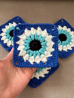 two crocheted blue and white coasters with black center being held by a person's hand