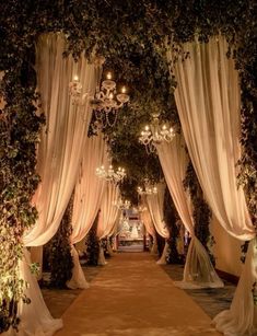 an aisle decorated with white drapes and chandeliers