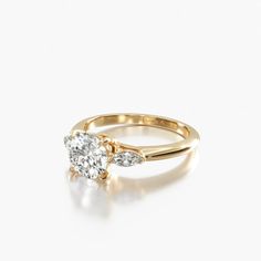 a gold engagement ring with two diamonds on top and side stones in the middle, against a white background