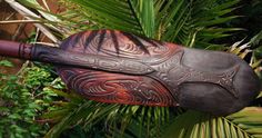 an intricately carved wooden baseball bat hanging from a palm tree