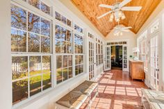 the inside of a house with large windows and wood ceiling beams, along with tile flooring