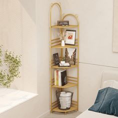 a gold shelf with books and pictures on it in the corner of a room next to a bed