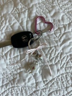 two heart shaped keychains on top of a white bed with a pink handle