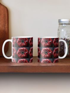 two coffee mugs sitting next to each other on a wooden shelf near a jar