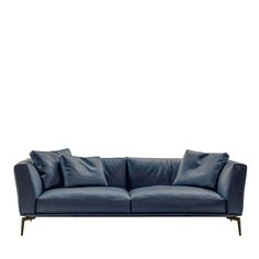 a blue leather couch with pillows on it's back and arms, against a white background