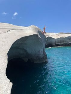 a person jumping off a cliff into the ocean