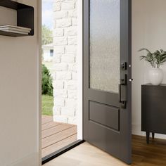 A black door with glass opens to a modern home with wood floors and off-white walls Black Exterior Doors, Black Interior Doors