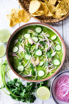 a bowl filled with cucumber, onions and cilantros next to tortilla chips