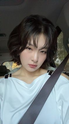 a young woman sitting in the back seat of a car wearing a white shirt and black suspenders