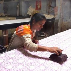 a woman sitting at a table working on something