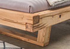 a wooden bed frame sitting on top of a carpeted floor next to a white rug