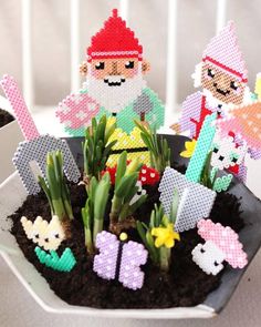 some little pixelated people are sitting in a potted planter with succulents