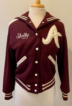 "Get your game on in full Classic Throwback with this Vintage 1990's Varsity Jacket.  Features a bomber jacket styling, 7 white snaps for closure, a 3\" striped sock bottom and a Classic Sailor collar which makes this such a rare beauty.  The name Shelly can be easily taken off and your name added.  Fully lined and ready to go!   Maker:  Butwin Tailoring, the Champion of Jackets Tag:  no size fits like a small  Condition:  really good, no stains, or holes, or fading in the color  Please check me Varsity Jacket With Button Closure For College, White Varsity Jacket With Button Closure, Sporty Varsity Jacket For College With Button Closure, White Cotton Varsity Jacket With Button Closure, White Hooded Varsity Jacket With Ribbed Cuffs, Fitted Varsity Jacket With Button Closure For College, Winter Varsity Jacket With Snap Buttons, Retro Varsity Jacket With Letter Print, White Baseball Collar Track Jacket For Fall