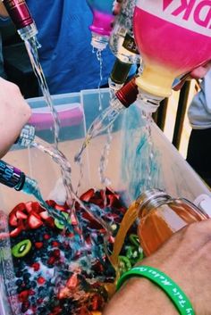 two people are pouring wine into a bucket filled with confetti and streamers