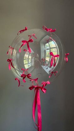 a clear balloon with pink ribbons on it and a round window in the back ground