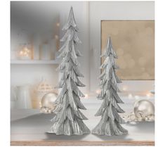 two silver christmas trees sitting on top of a table