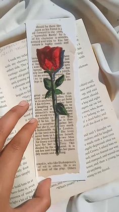 a person is holding an open book with a rose on it and the pages have been torn off