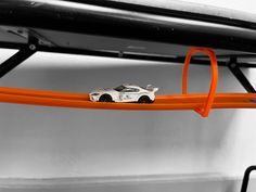 a toy car is sitting on top of an orange track in front of a black and white background