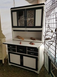 a white and black cabinet sitting on top of a grass covered field next to a window