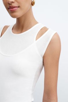 A sleeveless version of our much-loved Carson Top, Thea offers a strikingly unique neckline. Two layers of sheer, high-stretch European jersey combine with cutouts to create the look of a halter neckline layered with a classic round neck silhouette. With a sleek fit and edgy visual interest, Thea's an original alternative to your traditional tank that's day or night-ready.[SPLIT] Sam, in black and in spring green, is 5'8" (173 cm) tall, wearing size XS. Astrid, in off white and in raspberry, is Layered T-shirt, Stretch High Neck Tank Top For Summer, Elegant Sleeveless Cutout Top, Sleeveless Summer Tops With Cutout Back, Sleeveless Tops With Cutout Back For Summer, Fitted Sleeveless Top With Cutout Back, Chic Sleeveless Cutout Back Tank Top, Fitted Sleeveless Tops With Cutout Back, Chic Sleeveless Tank Top With Cutout Back