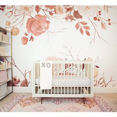 a white crib in front of a floral wall mural