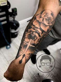 a man with a cross and rose tattoo on his arm