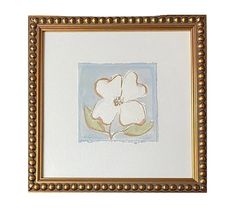 a white flower with green leaves in a gold frame