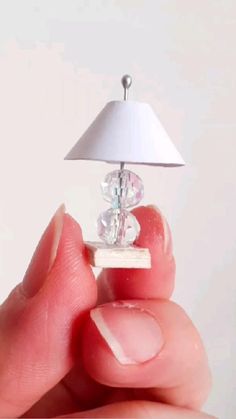 a tiny lamp sitting on top of a small piece of white paper in someone's hand