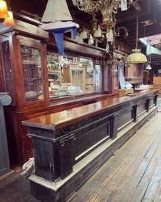 an old fashioned bar is in the middle of a room with wooden floors and chandeliers hanging from the ceiling