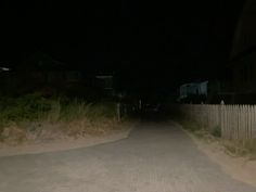 an empty street at night with no cars on it and houses in the background,