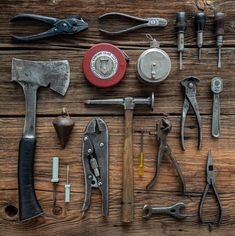 many different tools are laid out on a wooden surface, including hammers, pliers and wrenches