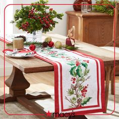 a christmas table runner with holly and red berries on it, along with other holiday decorations