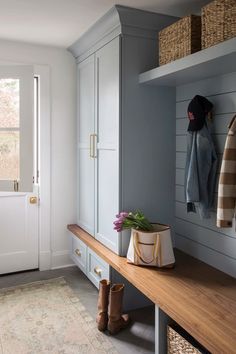 a wooden bench sitting under a window next to a coat rack and shoe box on top of a shelf