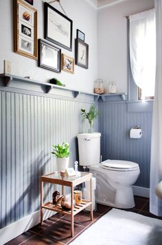 a white toilet sitting in a bathroom next to a wooden shelf with pictures on it