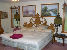 a large bed sitting in a bedroom next to two lamps and pictures on the wall