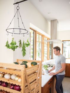 a man standing in front of a kitchen island with vegetables on it and hanging from the ceiling