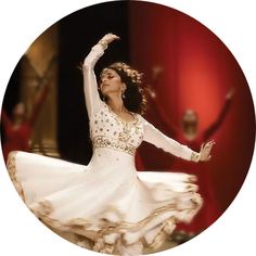 a woman in a white dress is dancing with other dancers behind her on the stage