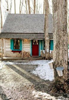 a small cabin in the woods with snow on the ground